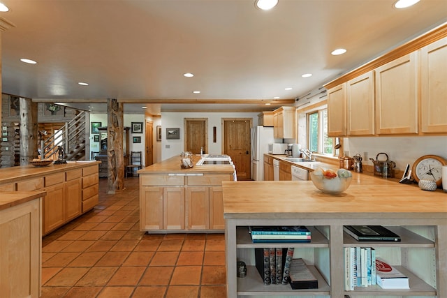 kitchen featuring light brown cabinets, wood counters, light tile floors, dishwasher, and sink