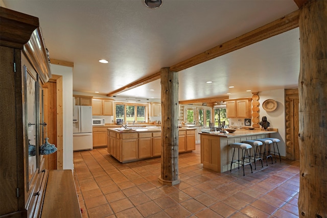 kitchen with light brown cabinetry, white appliances, light tile floors, a kitchen breakfast bar, and kitchen peninsula