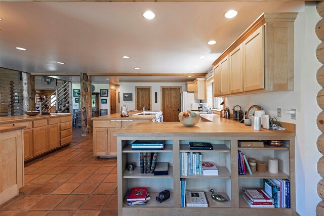 kitchen with light brown cabinets, white refrigerator, butcher block counters, sink, and tile floors