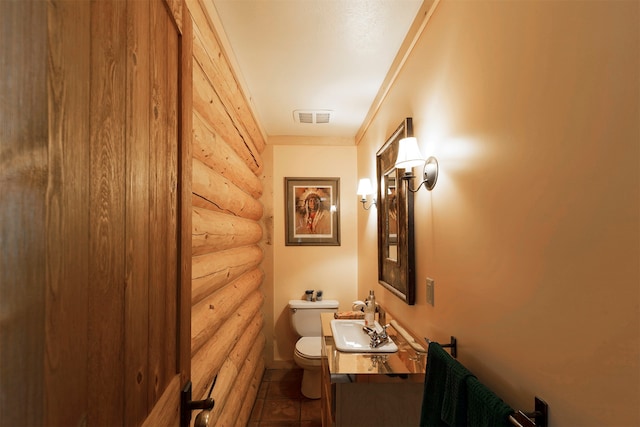 bathroom with vanity, tile floors, toilet, and rustic walls