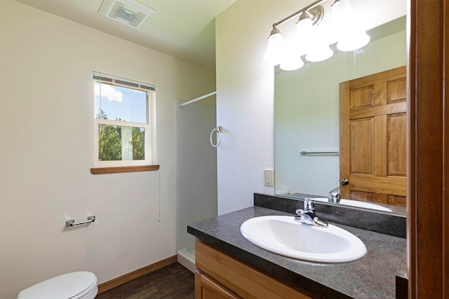 bathroom featuring toilet, vanity with extensive cabinet space, and wood-type flooring