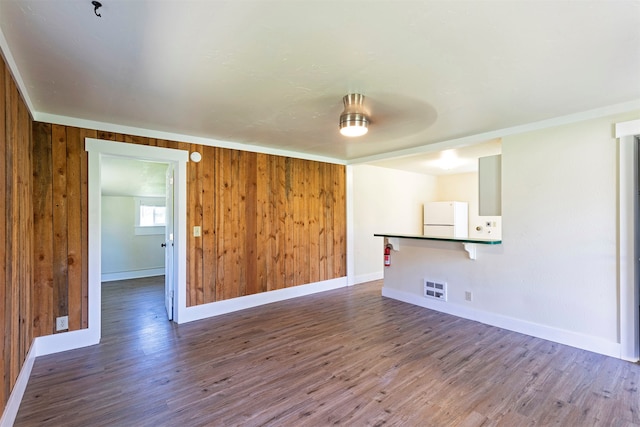 spare room featuring hardwood / wood-style floors, wood walls, and ceiling fan