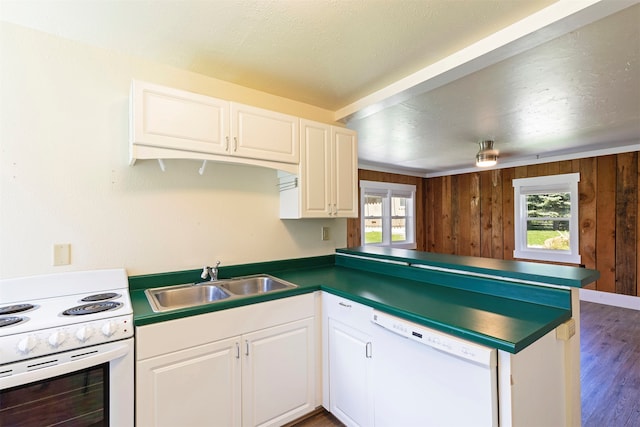 kitchen with hardwood / wood-style floors, white appliances, sink, wood walls, and white cabinets