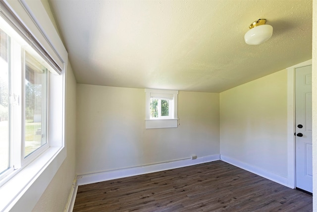 empty room featuring a textured ceiling and dark hardwood / wood-style flooring