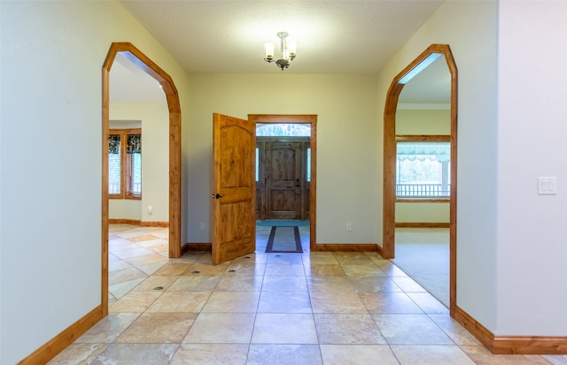 foyer entrance with crown molding and a chandelier