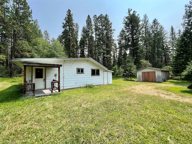 rear view of house featuring a yard and an outdoor structure