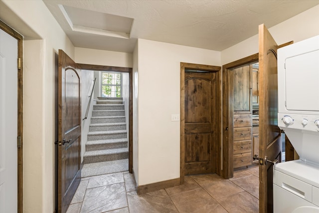 bathroom with tile floors and stacked washer / dryer