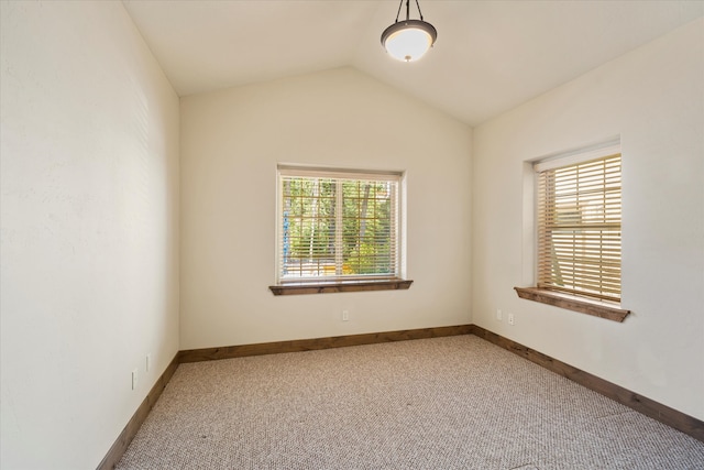 carpeted spare room with vaulted ceiling