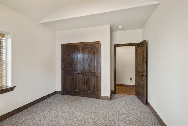 unfurnished bedroom with lofted ceiling and dark carpet