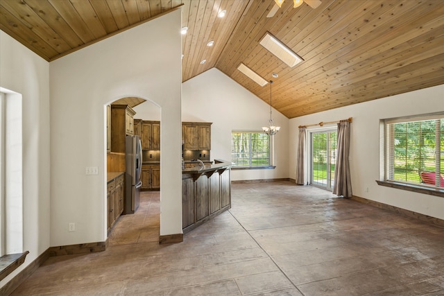 kitchen with pendant lighting, high vaulted ceiling, a skylight, wood ceiling, and stainless steel refrigerator with ice dispenser