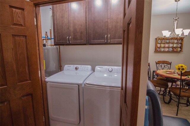 clothes washing area featuring separate washer and dryer, gas water heater, and a chandelier