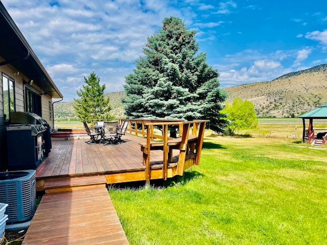 wooden deck with a gazebo, central AC unit, area for grilling, a lawn, and a mountain view