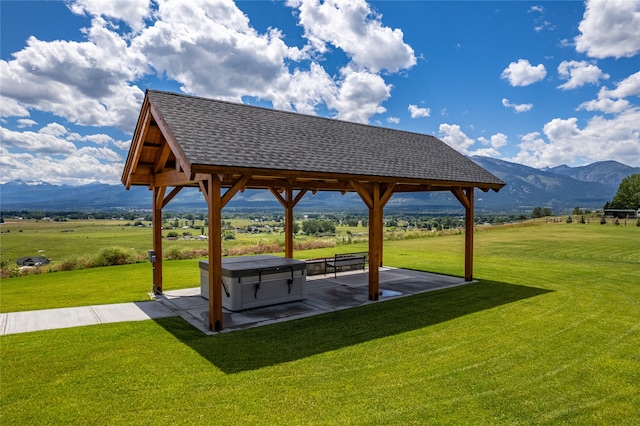 view of property's community featuring a mountain view, a patio area, a lawn, and a rural view