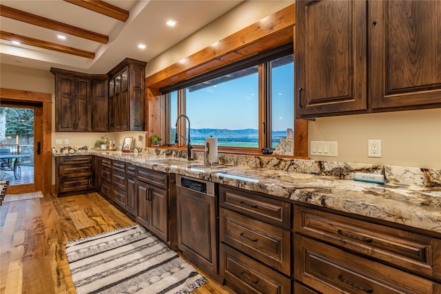 kitchen with sink, dark brown cabinetry, light wood-type flooring, a mountain view, and beam ceiling