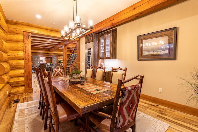 dining room with log walls, a chandelier, light wood-type flooring, and beam ceiling