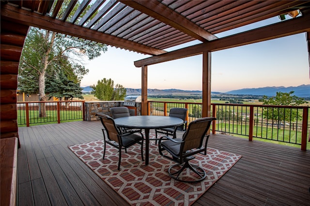 deck at dusk with a mountain view and a pergola