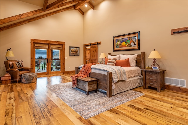 bedroom featuring beam ceiling, a barn door, wood-type flooring, and access to exterior