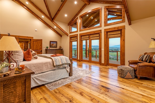 bedroom featuring hardwood / wood-style flooring, access to exterior, a mountain view, and high vaulted ceiling