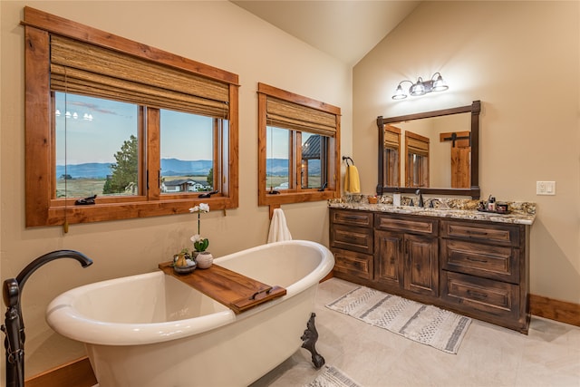 bathroom with plenty of natural light, a washtub, a mountain view, and vaulted ceiling