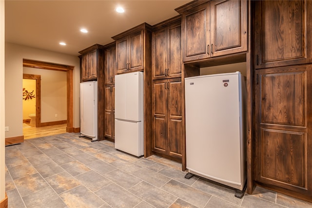 kitchen with dark brown cabinets, hardwood / wood-style flooring, and white refrigerator