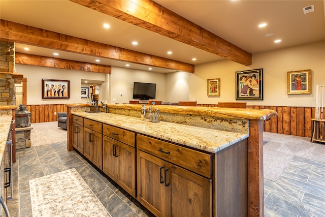 kitchen featuring dark colored carpet, light stone countertops, and a center island with sink