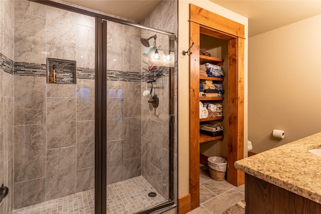 bathroom with vanity, a shower with shower door, toilet, and tile patterned flooring