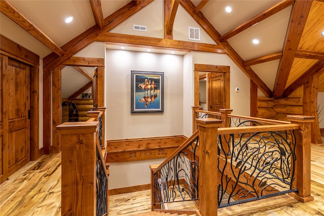 stairway featuring lofted ceiling with beams and light hardwood / wood-style floors