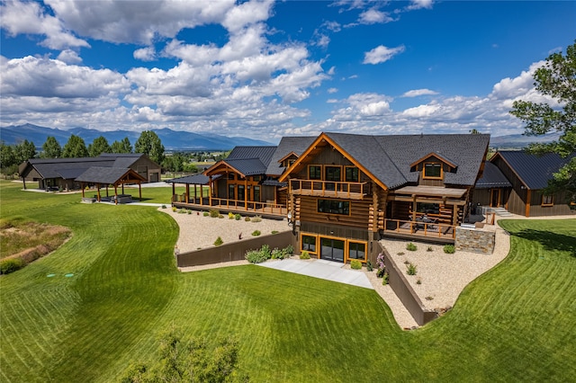 rear view of house with a mountain view and a yard