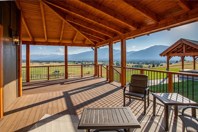 wooden terrace featuring a mountain view and a lawn