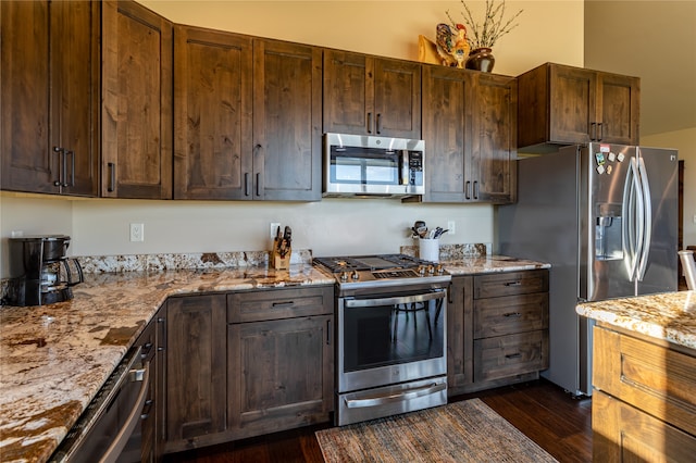 kitchen with dark wood-type flooring, light stone counters, and appliances with stainless steel finishes