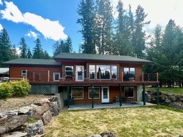 rear view of property with a patio, a wooden deck, and a lawn