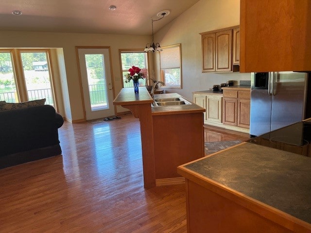 kitchen featuring stainless steel fridge with ice dispenser, lofted ceiling, wood-type flooring, a chandelier, and sink