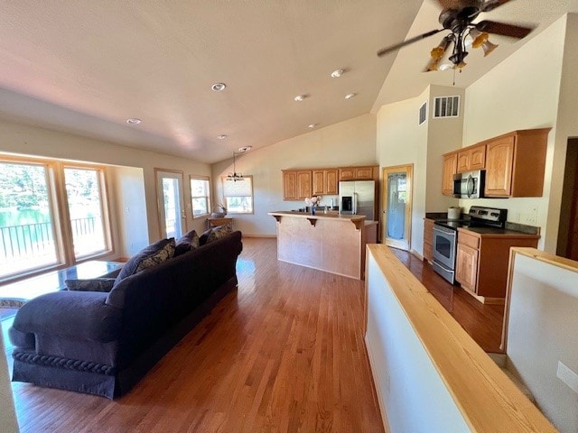 living room with wood-type flooring, lofted ceiling, plenty of natural light, and ceiling fan