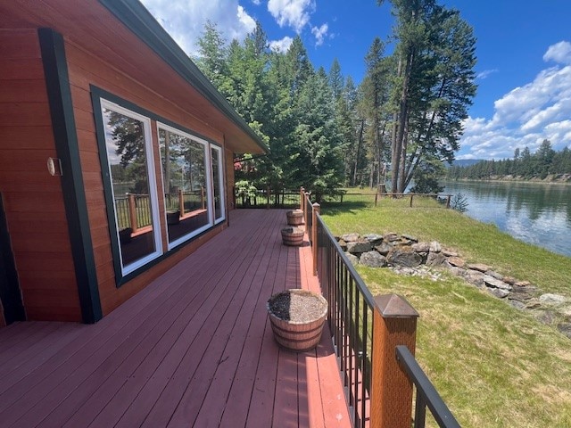 wooden terrace with a water view and a lawn