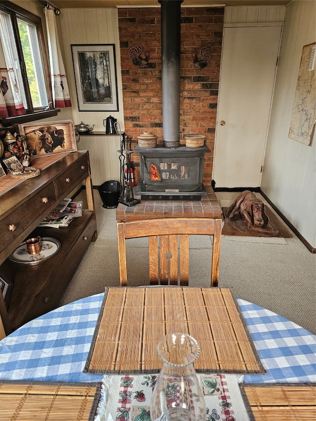 living room featuring a wood stove, brick wall, and carpet