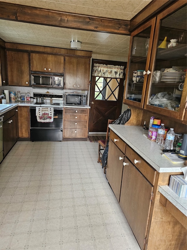 kitchen with light tile flooring, sink, dark brown cabinetry, and electric range