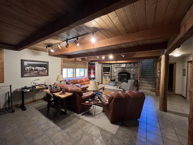 tiled living room with beam ceiling, a stone fireplace, wood ceiling, and rail lighting