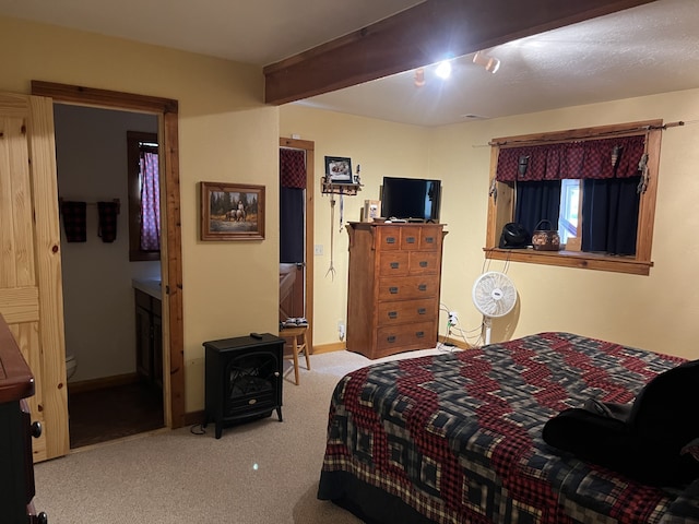 bedroom with beam ceiling, ensuite bath, and light colored carpet