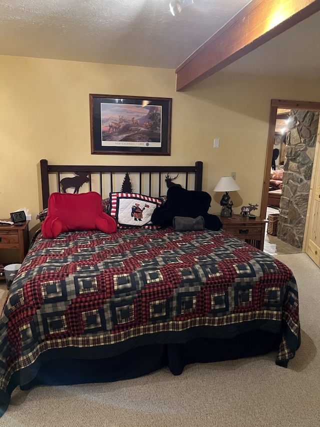 carpeted bedroom with beamed ceiling and a fireplace