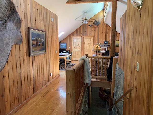 interior space with vaulted ceiling with beams, light hardwood / wood-style floors, and wooden walls