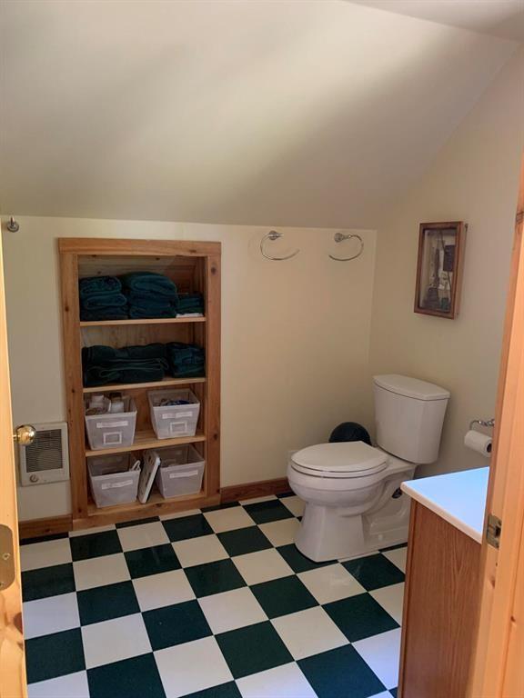 bathroom featuring toilet, vanity, heating unit, and vaulted ceiling