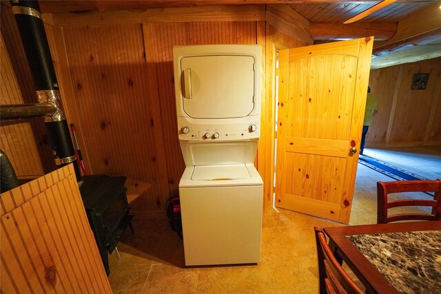 laundry area featuring light tile flooring and stacked washer / drying machine