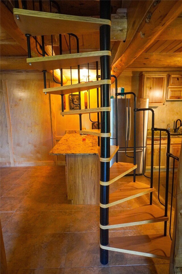 stairway featuring wooden walls, dark tile floors, and sink