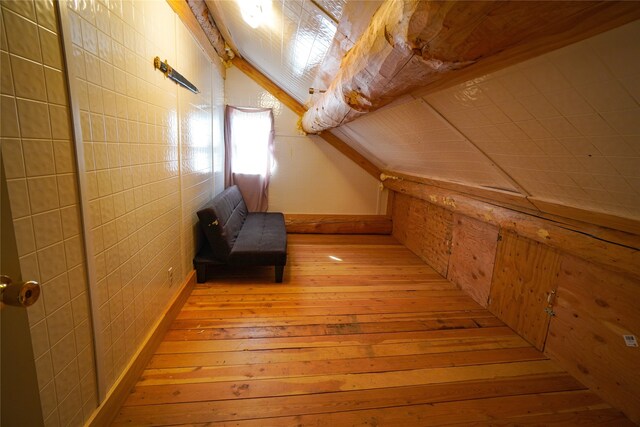 bonus room with lofted ceiling and light wood-type flooring