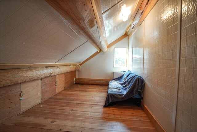 bonus room with light wood-type flooring and lofted ceiling with beams