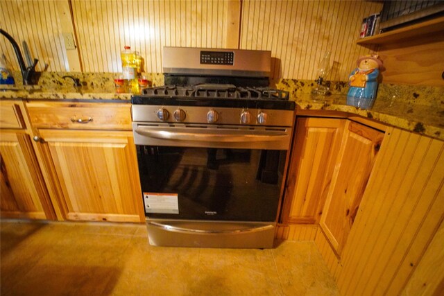 kitchen with tile flooring, gas range, and light stone counters