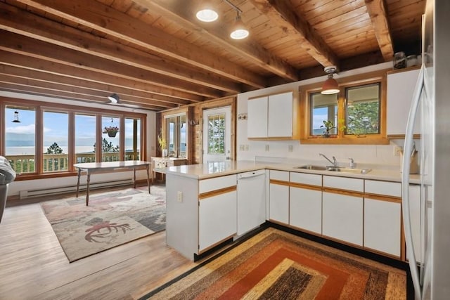 kitchen with a peninsula, dishwasher, white cabinets, and light countertops