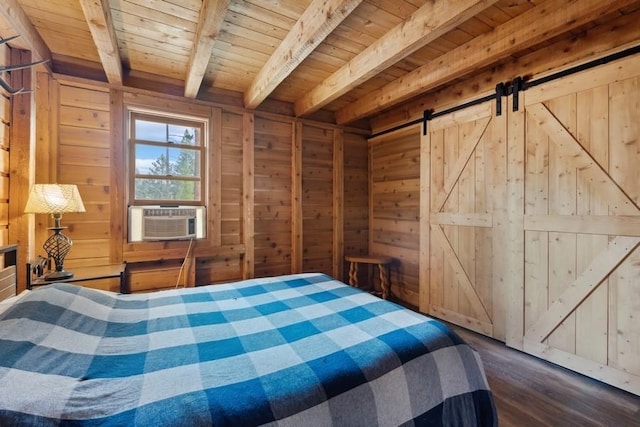 unfurnished bedroom with beam ceiling, dark wood finished floors, a barn door, wooden walls, and wooden ceiling