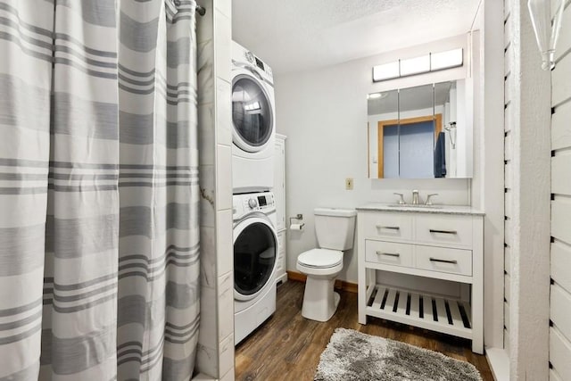 washroom featuring laundry area, stacked washer / dryer, dark wood-style floors, a textured ceiling, and a sink