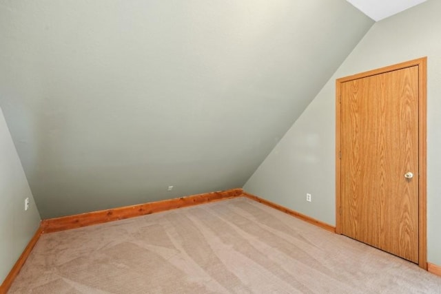 bonus room with lofted ceiling, baseboards, and light colored carpet